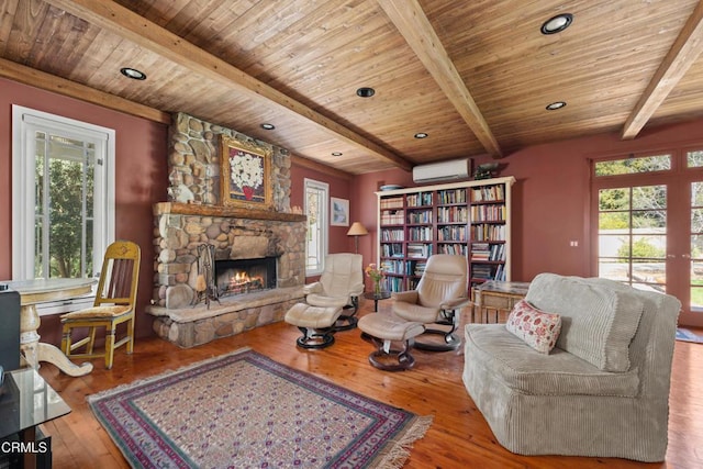 living room featuring wood ceiling, a stone fireplace, an AC wall unit, and hardwood / wood-style flooring