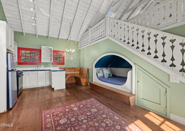 interior space featuring dark wood-style floors, high vaulted ceiling, beam ceiling, freestanding refrigerator, and a sink