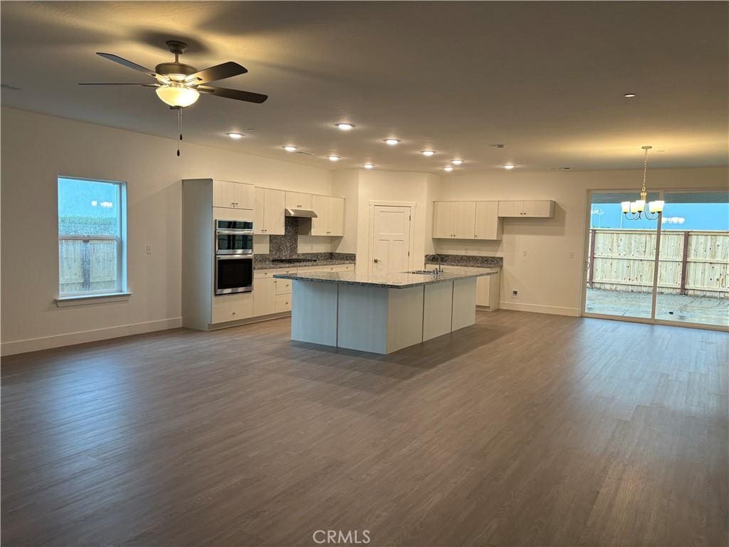 3821 Via Santa Barbara Ave, Madera, CA 93637 - kitchen featuring appliances with stainless steel finishes, a chandelier, white cabinets, a kitchen island with sink, and dark wood-type flooring