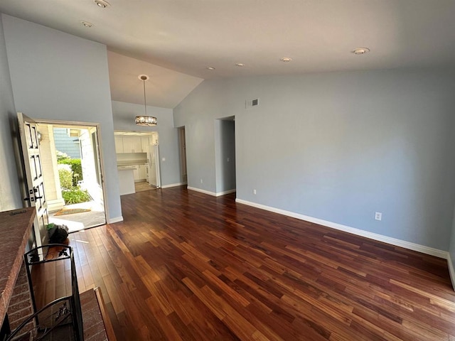 unfurnished living room with visible vents, dark wood-style floors, an inviting chandelier, baseboards, and vaulted ceiling