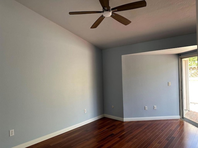 spare room with baseboards, a ceiling fan, and dark wood-style flooring