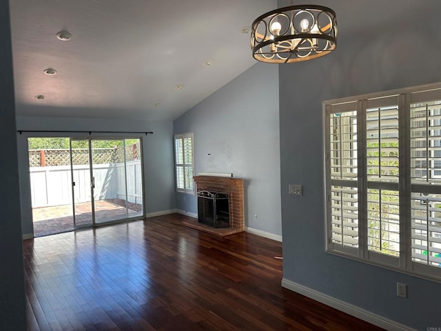 unfurnished living room featuring a brick fireplace, wood finished floors, baseboards, and a chandelier