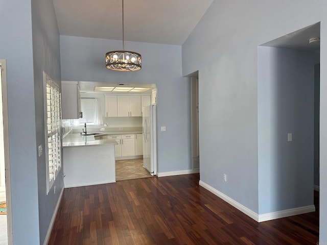 kitchen featuring baseboards, freestanding refrigerator, hardwood / wood-style flooring, light countertops, and a chandelier