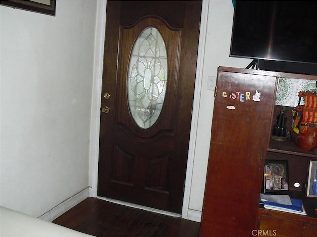 foyer featuring baseboards and dark wood-style floors