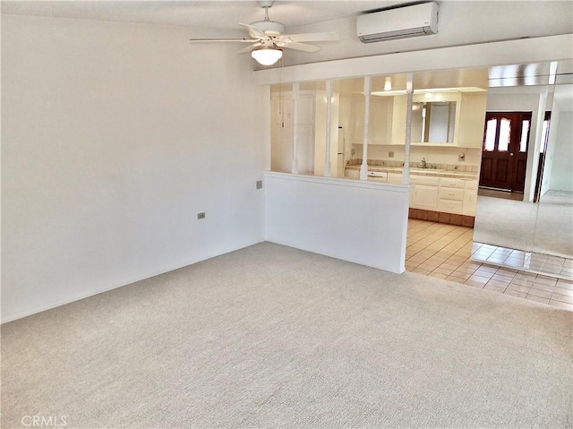 interior space with light tile patterned floors, ceiling fan, a sink, a wall mounted air conditioner, and light colored carpet