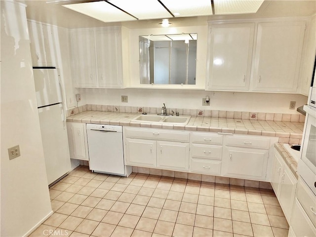 kitchen featuring light tile patterned floors, white cabinets, white appliances, and a sink