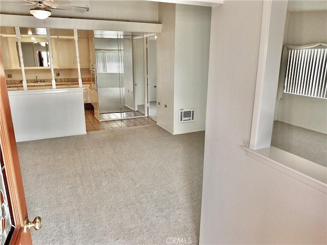 tiled empty room featuring ceiling fan and carpet flooring