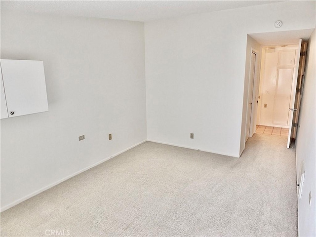 spare room with light carpet and baseboards