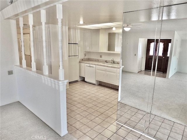 kitchen featuring a ceiling fan, a sink, white appliances, light tile patterned flooring, and tile counters