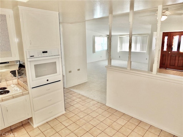 kitchen with tile countertops, light colored carpet, light tile patterned floors, white cabinets, and white appliances