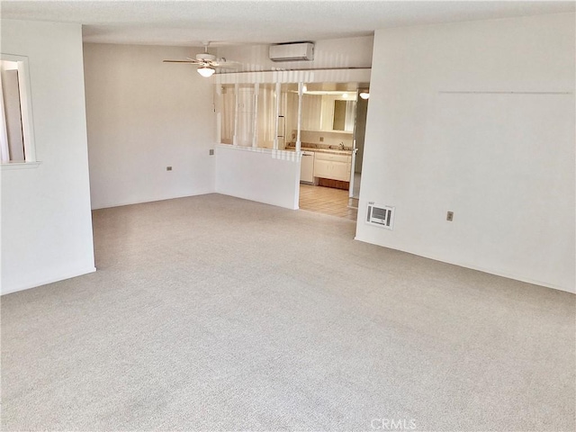 empty room with visible vents, light carpet, an AC wall unit, a sink, and ceiling fan