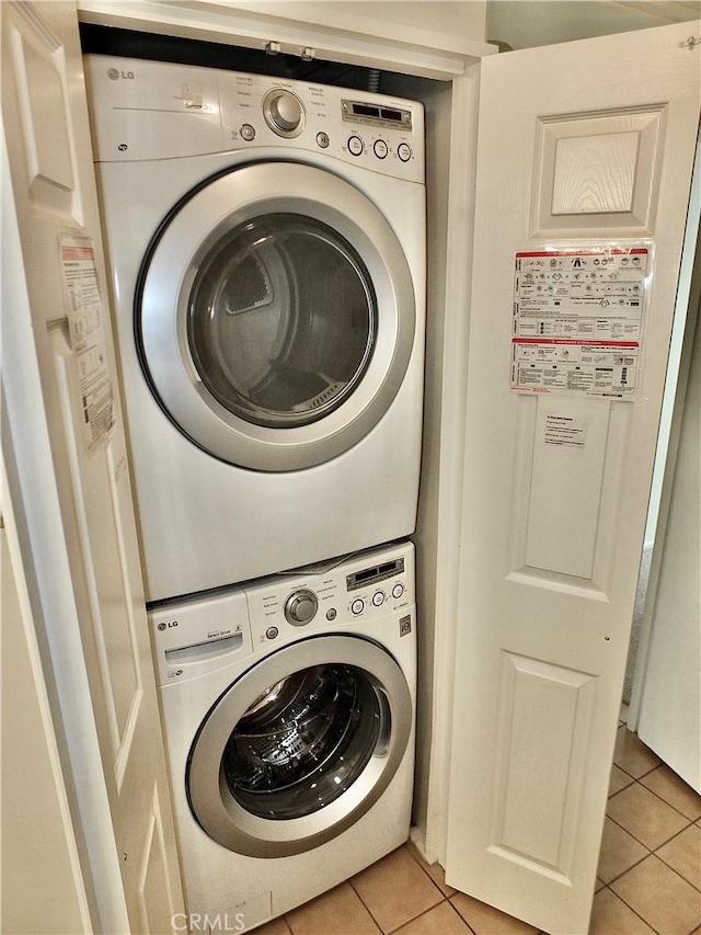 washroom featuring light tile patterned flooring, laundry area, and stacked washer and clothes dryer