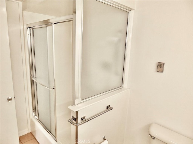 full bath with toilet, bath / shower combo with glass door, and tile patterned flooring