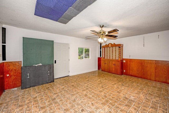10670 Olive Grove Ave, Sunland, CA 91040 - empty room with ceiling fan, a textured ceiling, wainscoting, and wooden walls