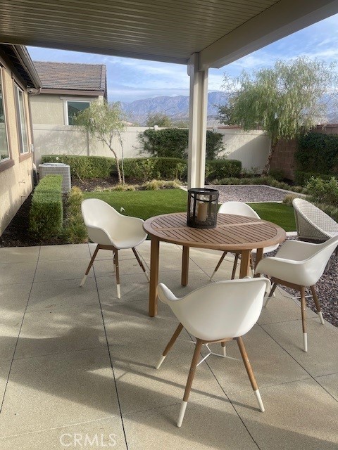 view of patio with outdoor dining area, central AC unit, a mountain view, and a fenced backyard