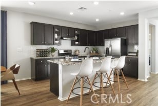 kitchen featuring wood finished floors, a breakfast bar, range hood, and light countertops