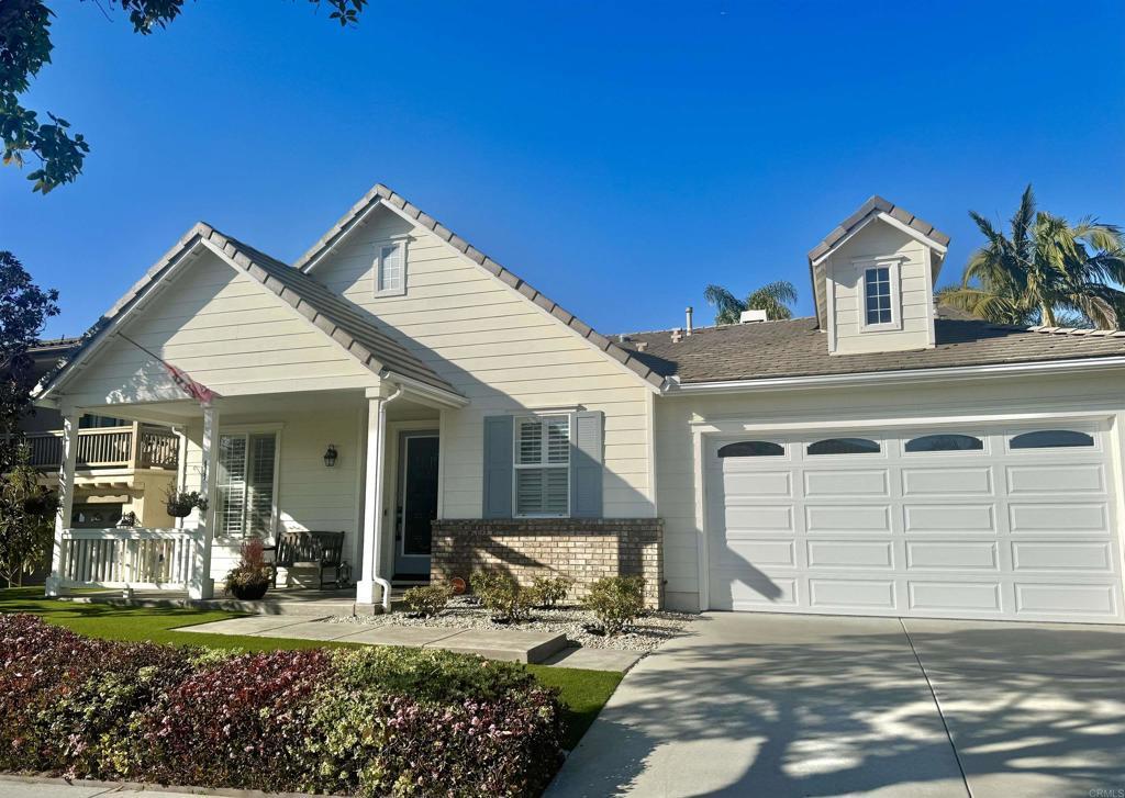 view of front of house featuring a tile roof, covered porch, concrete driveway, a garage, and brick siding