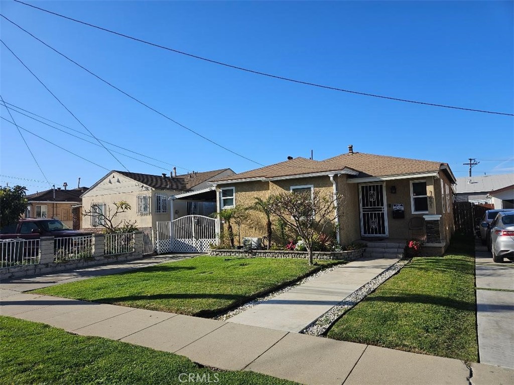 view of front of property featuring a gate, a fenced front yard, a front lawn, and stucco siding