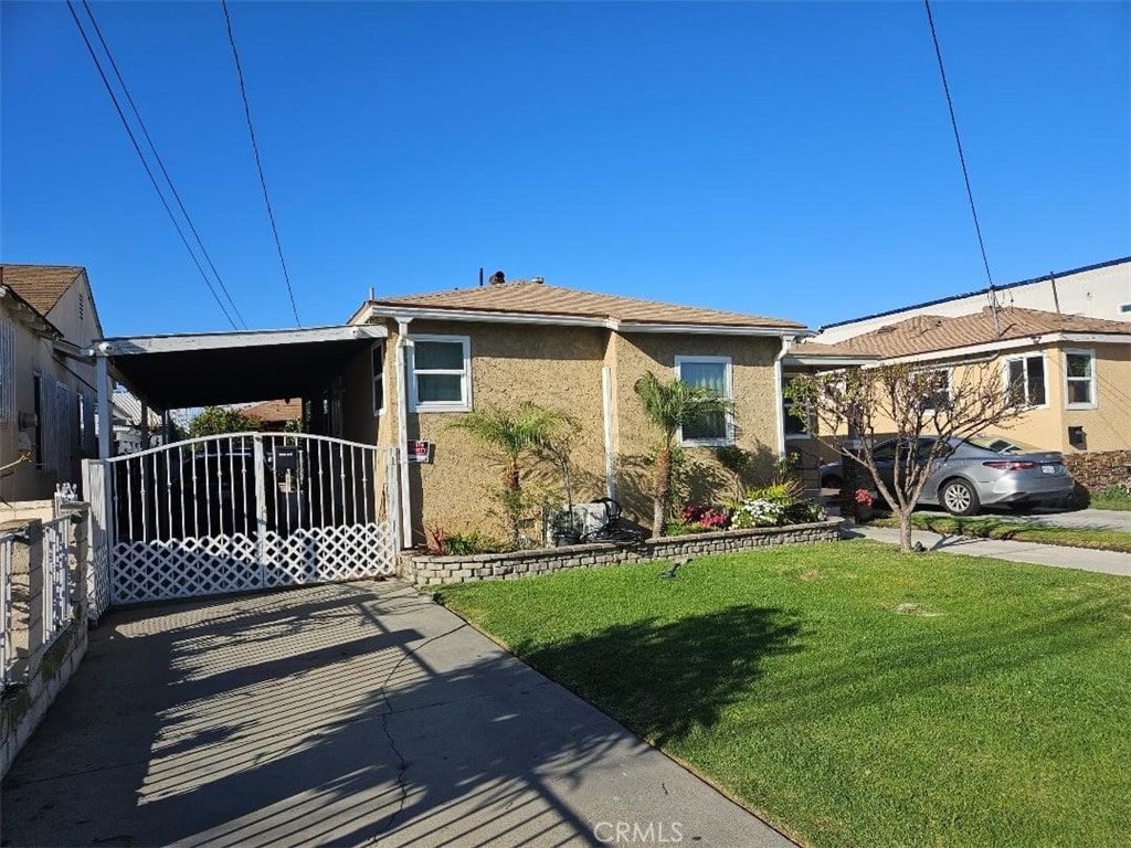 view of front of home featuring a front lawn, a carport, and stucco siding