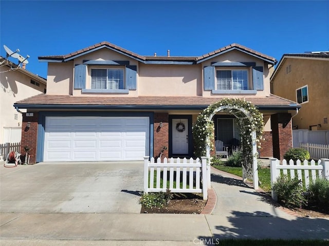 view of front of property featuring a tile roof, a fenced front yard, concrete driveway, an attached garage, and brick siding