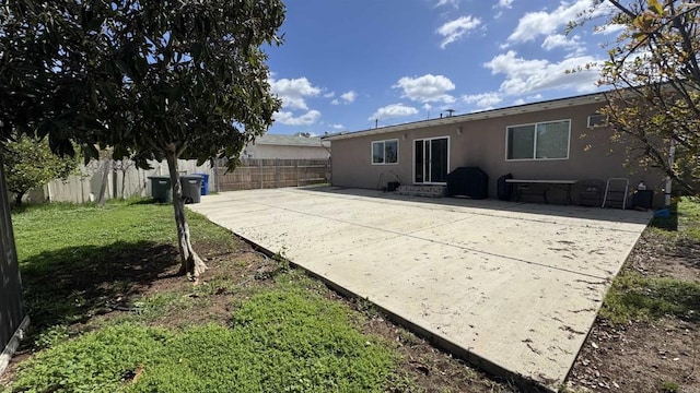 back of property featuring entry steps, stucco siding, a lawn, a fenced backyard, and a patio