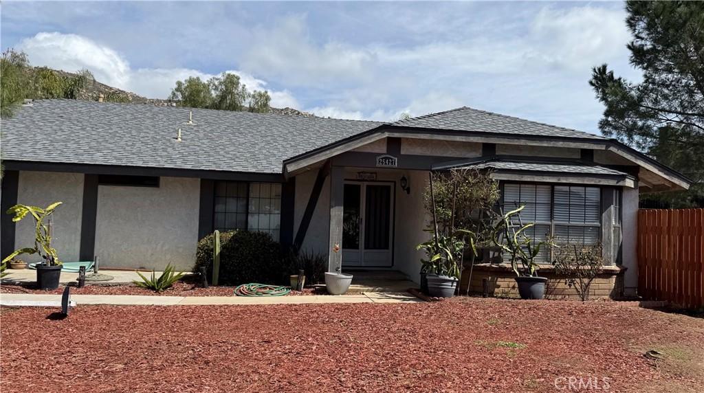 view of front of house featuring stucco siding, roof with shingles, and fence