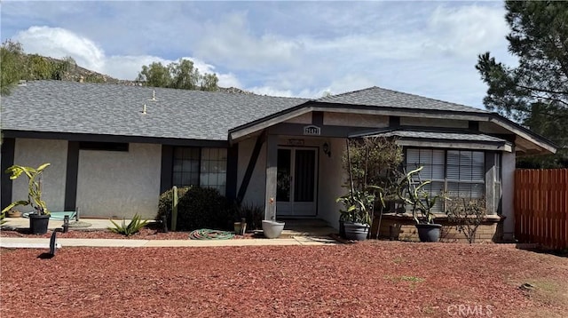 view of front of house featuring stucco siding, roof with shingles, and fence