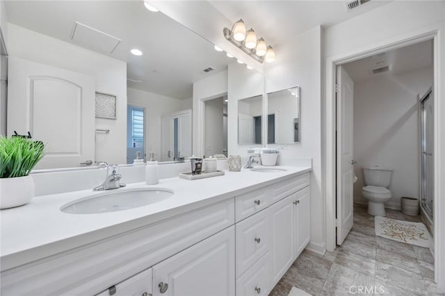 bathroom featuring double vanity, toilet, a stall shower, and a sink