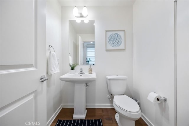 bathroom featuring toilet, baseboards, and wood finished floors