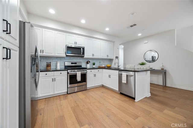 kitchen featuring dark countertops, appliances with stainless steel finishes, white cabinetry, and a sink