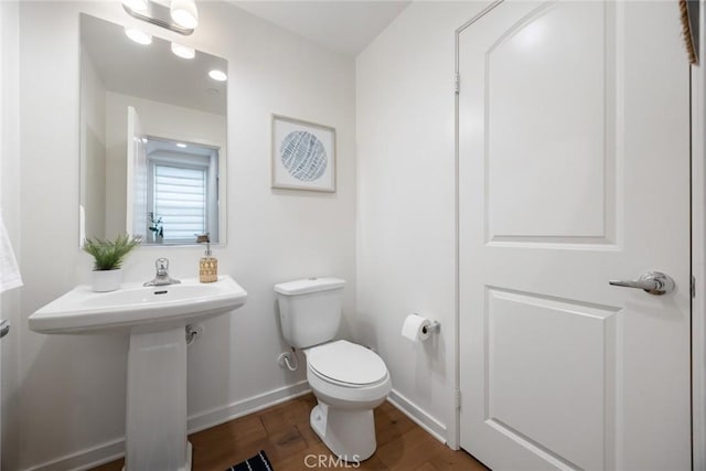 bathroom with a sink, baseboards, toilet, and wood finished floors