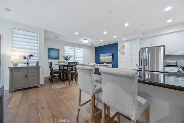 kitchen featuring recessed lighting, stainless steel fridge, white cabinets, and light wood-type flooring