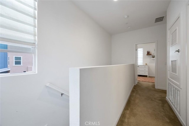 hallway with carpet flooring, an upstairs landing, visible vents, and baseboards