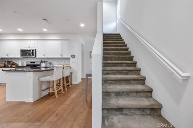 stairway featuring visible vents, recessed lighting, and hardwood / wood-style floors