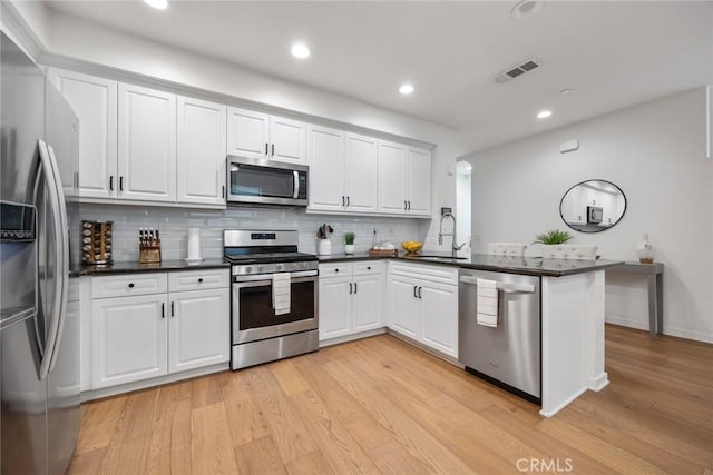 kitchen featuring dark countertops, visible vents, appliances with stainless steel finishes, and a sink