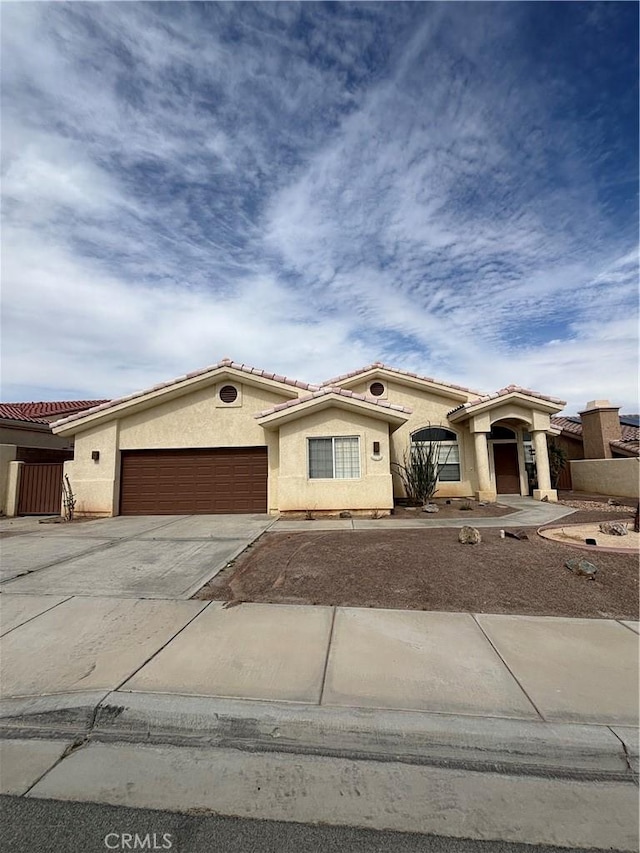 mediterranean / spanish house with stucco siding, driveway, a tile roof, and a garage