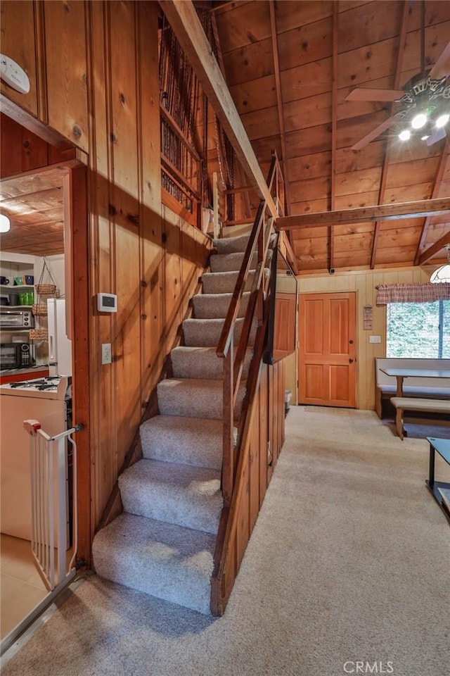 23679 Hillside Dr, Crestline, CA 92325 - staircase with wood walls, ceiling fan, carpet, wood ceiling, and vaulted ceiling with beams
