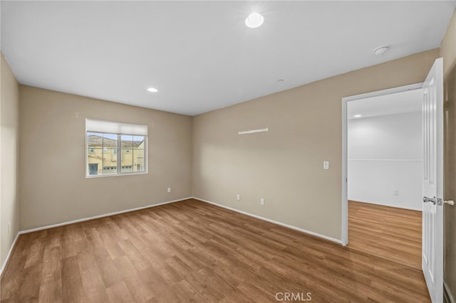 spare room with recessed lighting, baseboards, and wood finished floors