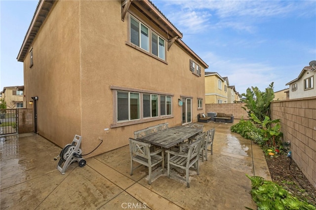rear view of house with a fenced backyard, stucco siding, a patio area, and outdoor dining area