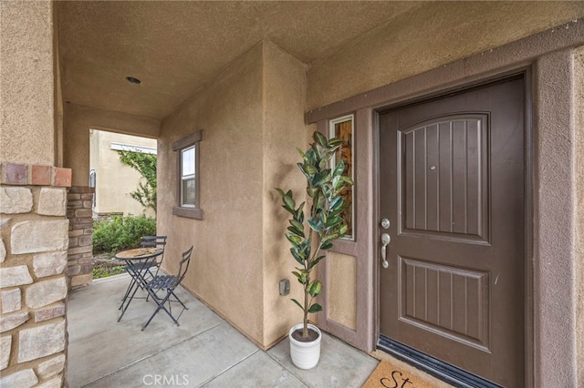 entrance to property with stucco siding and a patio