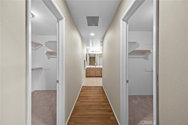 corridor with dark carpet, baseboards, and visible vents