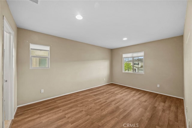 unfurnished room featuring baseboards, wood finished floors, and recessed lighting