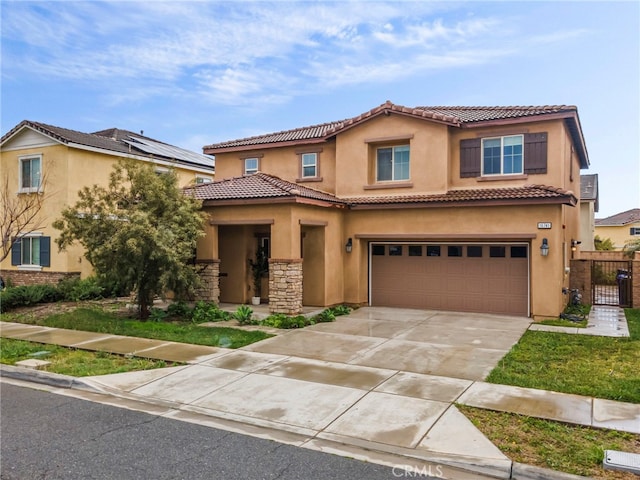 mediterranean / spanish home featuring stucco siding, an attached garage, a tiled roof, driveway, and a gate