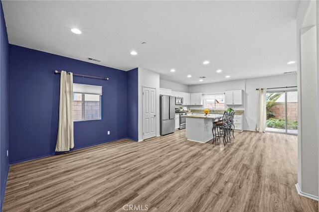 kitchen with white cabinetry, light wood-style flooring, stainless steel appliances, and visible vents