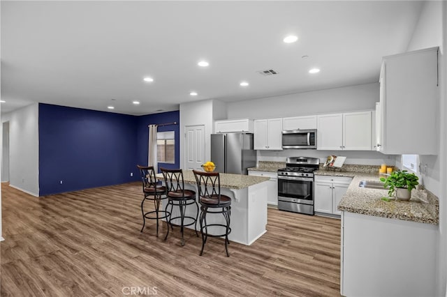 kitchen with a breakfast bar, a kitchen island, light wood-style floors, visible vents, and appliances with stainless steel finishes