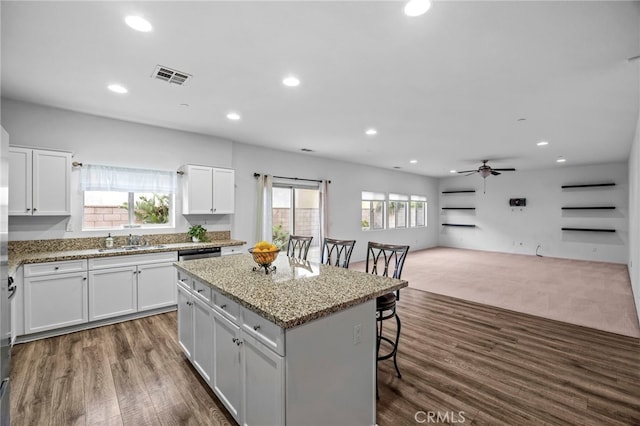 kitchen featuring a sink, a kitchen bar, a center island, visible vents, and ceiling fan