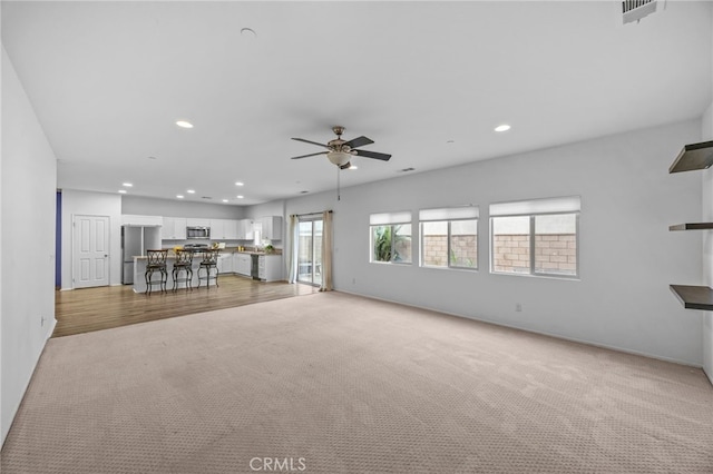 unfurnished living room with a ceiling fan, visible vents, light carpet, and recessed lighting