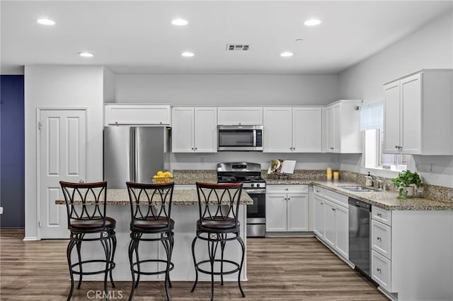 kitchen featuring white cabinets, a sink, a center island, and appliances with stainless steel finishes