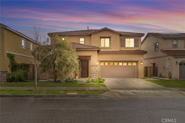 mediterranean / spanish-style home with a tile roof, stucco siding, an attached garage, stone siding, and driveway