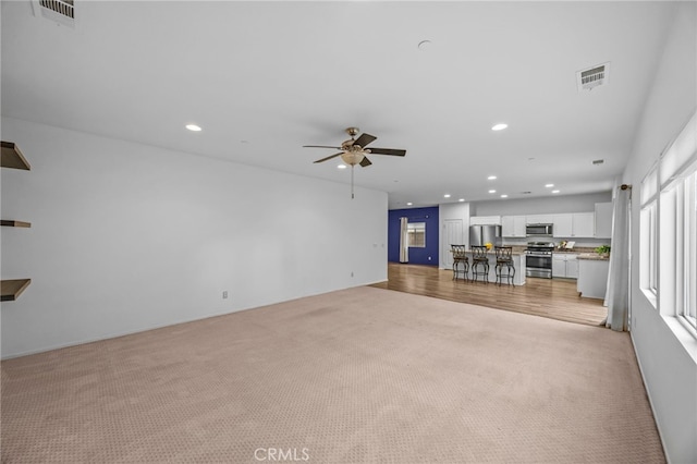 unfurnished living room with light colored carpet, visible vents, recessed lighting, and a ceiling fan